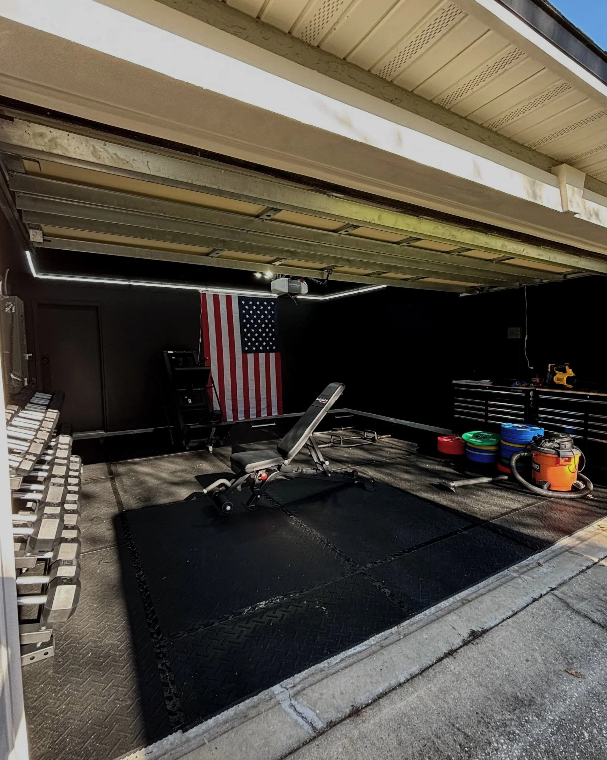 Garage home gym with an adjustable bench and weight plates in Jacksonville, FL