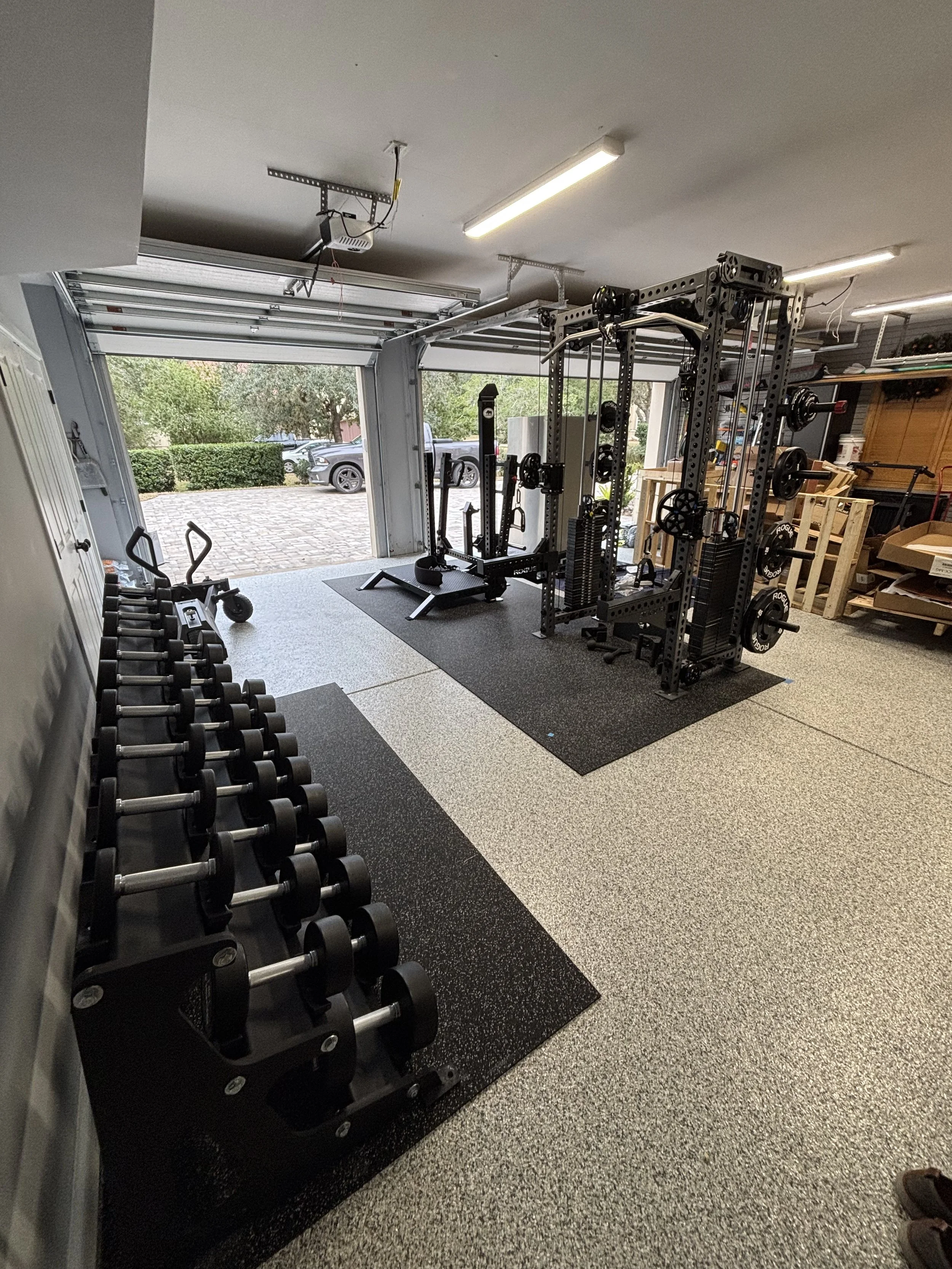 Home gym with a power rack and dumbbells assembled in a Jacksonville, FL garage